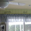 Wall words on a green colored wall above the curtain draperies with picture frames beside the window
