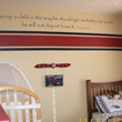 Train up a child on the way he should go and when he is old, he will not depart from it on the center of a wall above the red and blue wallpaper partition, with crib and bed in the Aviation themed boy's room