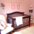 Wall quotes on the center of a baby girl's room, above the 2 wall picture frames and a wooden baby girl's crib