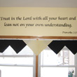 A wall decal quote from the bible above the window with colors white and dark brown drapery.