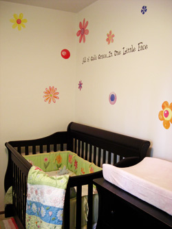 A wall decal in the baby's room with a wooden crib and a drawer -All of God's grace is one little face