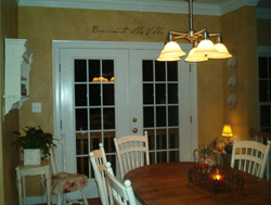 Benvenuto Alla Villa wall decal above the colonial glass paneled door with dining table and chairs in the dining room area