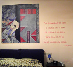 An Italian Shakespeare wall quote on the bedroom with the bed and the painting in the side.